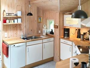 una cucina con pareti in legno, mobili bianchi e un lavandino di 6 person holiday home in Rødby a Rødby