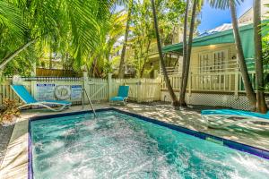 a swimming pool with two chairs and a house at Palm Gardens in Key West