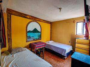 Cette chambre comprend 2 lits, une table et une fenêtre. dans l'établissement Casa Argentina, à San Juan La Laguna