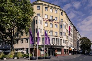 un bâtiment avec des drapeaux violets devant lui dans l'établissement Mercure Hotel Düsseldorf City Center, à Düsseldorf