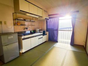 cocina con nevera, fregadero y ventana en Weekly Hotel Kokura, en Kitakyushu