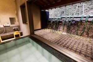 a swimming pool in a house with a shower at Yuraku Kinosaki Spa & Gardens in Toyooka