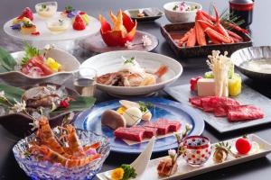 Yuraku Kinosaki Spa & Gardens في تويوكا: طاولة عليها العديد من أطباق الطعام