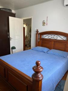 Un dormitorio con una gran cama de madera con sábanas azules en Casa, en São Gabriel