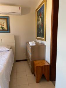 een slaapkamer met een bed, een dressoir en een schilderij bij Praia do Forte Condomínio Bali Bahia Apt105 in Praia do Forte