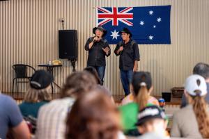 two men standing on a stage in front of a crowd at BIG4 Opal Holiday Park in Lightning Ridge