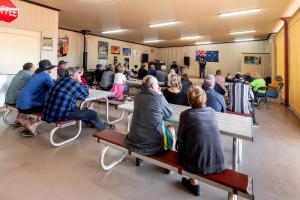 um grupo de pessoas sentadas em bancos em uma sala em BIG4 Opal Holiday Park em Lightning Ridge