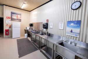 una cocina con encimeras de acero inoxidable y un reloj en la pared en BIG4 Opal Holiday Park, en Lightning Ridge