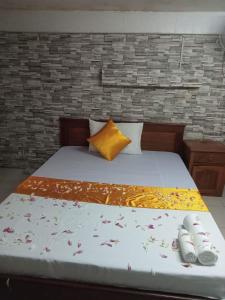 1 cama con almohada amarilla y 2 pares de zapatos en White River guesthouse en Phnom Penh