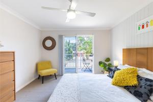 a bedroom with a bed and a yellow chair at 110 Catalina Close so close to the water in Shoal Bay