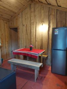 a picnic table in a room with a refrigerator at Cabañas Cauchao Chaitén in Chaitén