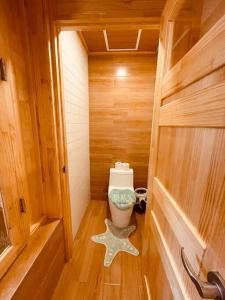 a small bathroom with a toilet in a wooden room at bebe angpang 2 in Seogwipo