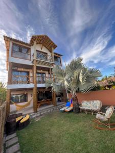 Costa Dourada的住宿－Recanto Bela Vista II，院子里有棕榈树和椅子的房子