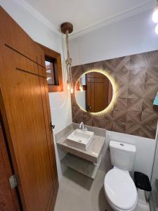 a bathroom with a toilet and a sink and a mirror at Recanto Bela Vista II in Costa Dourada