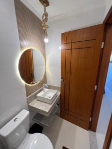 a bathroom with a toilet and a sink and a mirror at Recanto Bela Vista II in Costa Dourada