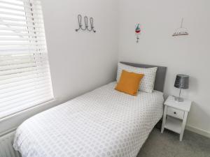 Dormitorio con cama con almohada naranja en Ty'r Winllan, en Newport