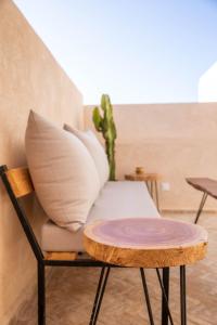 una silla con almohadas y una mesa con cactus en Surf&Sound Hotel, en Imsouane
