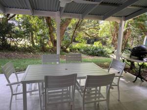 a table with chairs and a grill on a patio at Puddleduck Cottage at Maleny in Balmoral Ridge