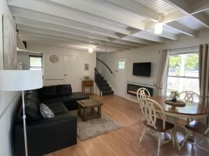 a living room with a black couch and a table at Puddleduck Cottage at Maleny in Balmoral Ridge