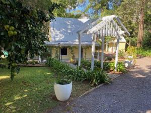 a white pergola in front of a house at Puddleduck Cottage at Maleny in Balmoral Ridge