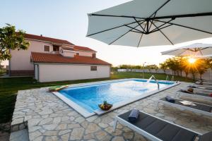 - une piscine avec un parasol à côté d'une maison dans l'établissement Holiday apartment in Privlaka with sea view, balcony, air conditioning, WiFi 3598-5, à Privlaka