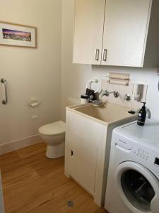 a bathroom with a washing machine and a toilet at Harrington Getaway in Harrington