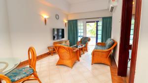 uma sala de estar com cadeiras, uma mesa e uma televisão em Long Sands Port Dickson em Porto Dickson