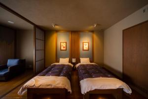 a room with two beds and a chair at Yukyo no Hibiki Yusai in Minamioguni