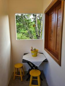 un tavolino con due sgabelli e una finestra di Villa Silva&Braga POUSADA arraial d'ajuda Bahia-VERDE a Arraial d'Ajuda