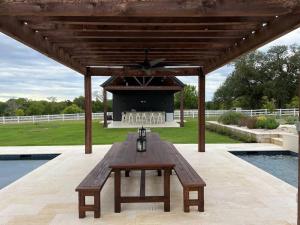 una mesa de picnic de madera sentada bajo un pabellón junto a una piscina en Beautiful 3BR Stay on stunning farm near Round Top, en Greenvine