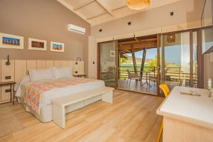 a bedroom with a bed and a balcony with a table at Hotel Ohana Rapa Nui in Hanga Roa