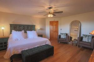 a bedroom with a bed with a ceiling fan and two chairs at Bells With a View in Sevierville
