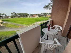 un balcón con mesa y sillas y un campo de golf en Appartement Capbreton, 3 pièces, 4 personnes - FR-1-239-608, en Capbreton