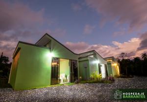 una casa verde con luces encendidas por la noche en Hospedaje Barrantes, en Coto Brus
