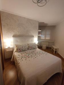 a bedroom with a white bed with flowers on it at Apartamento Pontevedra centro HOMYHOME II in Pontevedra