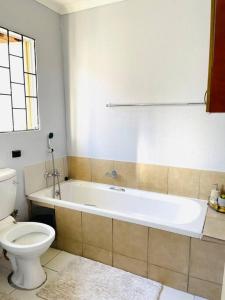 a bathroom with a white tub and a toilet and a sink at Are you travelling to Pretoria? in Pretoria