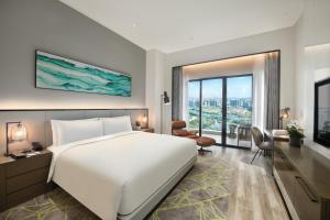 a bedroom with a large white bed and a large window at Oakwood Residence Foshan in Foshan