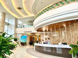 a lobby of a hotel with people standing at a counter at TTC Hotel - Michelia in Nha Trang