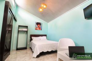 1 dormitorio con cama blanca y pared azul en Hospedaje Barrantes, en Coto Brus