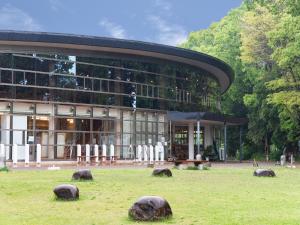 een gebouw met rotsen in het gras ervoor bij Hotel Primrose Saito in Saito