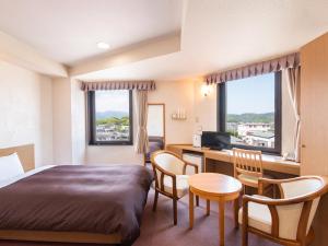 een hotelkamer met een bed en een bureau met een computer bij Hotel Primrose Saito in Saito