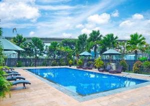 a large swimming pool with chairs and umbrellas at Le Premier Hotel Deltamas in Cikarang