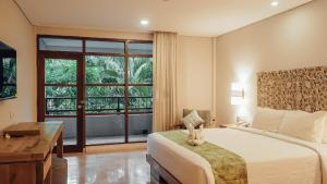 a bedroom with a bed and a desk and a window at AlamKulkul Boutique Resort in Kuta