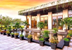 a building with a pond with potted plants in front of it at Le Premier Hotel Deltamas in Cikarang