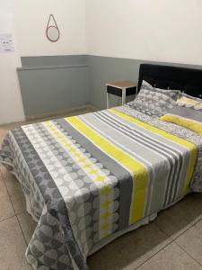 uma cama com uma colcha num quarto em Hostel Lize em Cumbica