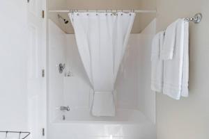 a white bathroom with a shower with white towels at Unique Barn Stay Close to The Hills in Rapid City