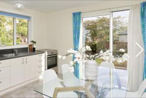 uma cozinha com uma mesa de vidro com um vaso de flores em Stump Cottage em Christchurch