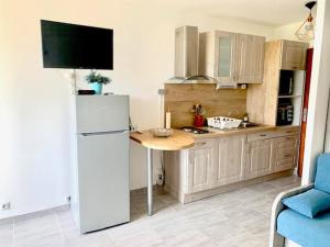kuchnia z białą lodówką i stołem w obiekcie Studio climatisé avec garage et WiFi à 5 min des Thermes - FR-1-503-157 w mieście Balaruc-les-Bains