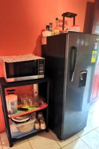 a kitchen with a microwave and a shelf with food at Starfish Cahuita's House - Casa Vacacional in Cahuita