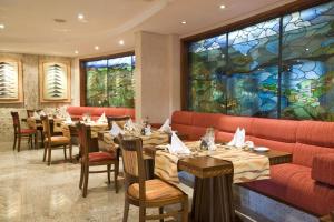 ein Restaurant mit Tischen und Stühlen und einem großen Fenster in der Unterkunft Kigali Serena Hotel in Kigali